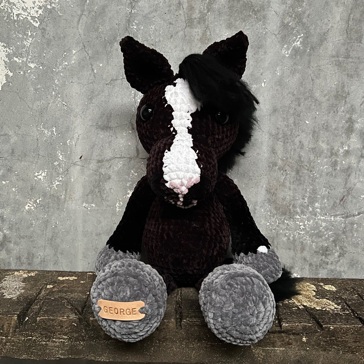 Knitted horse toy with a white star on a textured surface